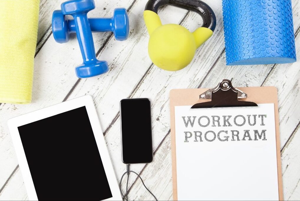 Phone, clipboard, and workout equipment symbolizing personalized fitness programs